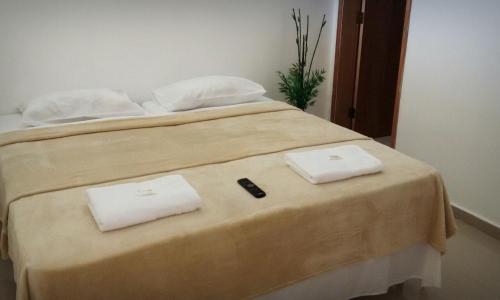 a bed with two white towels on top of it at Hospedagem de Jesus in Aparecida