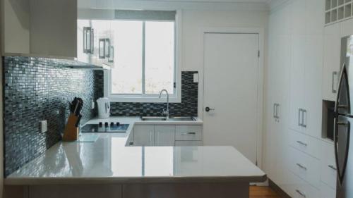 a white kitchen with a sink and a window at Boat Ramp Shack in Coffin Bay