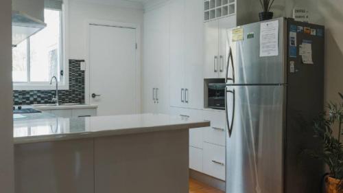 a kitchen with a stainless steel refrigerator and white cabinets at Boat Ramp Shack in Coffin Bay