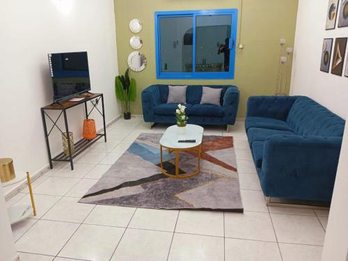 a living room with a blue couch and a table at Luxury 2-Bedroom Family Apartment on Buhaira Corniche in Sharjah