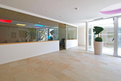 an office lobby with a white counter and a potted plant at Hotel Waldruhe in Gsies