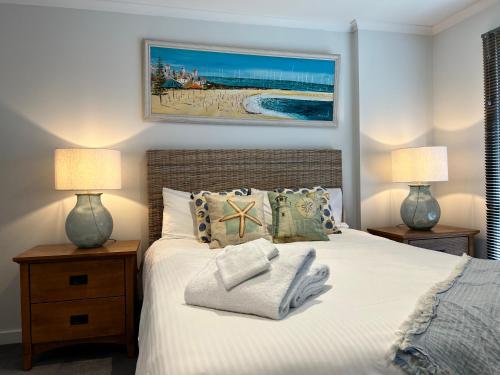 a bedroom with a bed with two lamps and towels on it at 2 Bedroom Townhouse - Close to Beach in Torquay