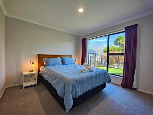 a bedroom with a large bed and a large window at Grand Getaway Te Anau in Te Anau