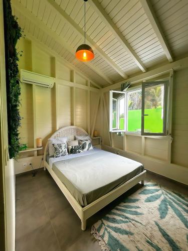 Un dormitorio con una cama en una habitación con ventana. en Villa Celiane, en Petit-Bourg