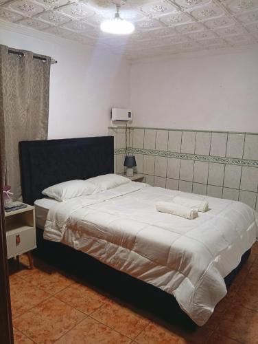 a bedroom with a large bed with white sheets at Casa de descanso in Alajuela City