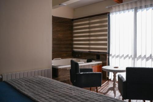 a bedroom with a tub and a bed and a table at Hotel Mitru in Tupiza