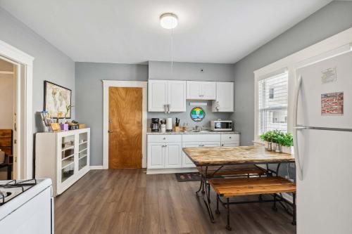 a kitchen with white cabinets and a wooden table at BrewLoft Cleveland - Near Rock Hall & Downtown in Lakewood