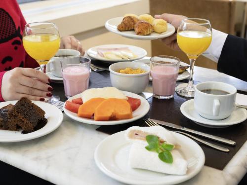 Un groupe de personnes assises à une table avec des assiettes de nourriture dans l'établissement Mercure Sao Paulo Grand Plaza Paulista, à São Paulo