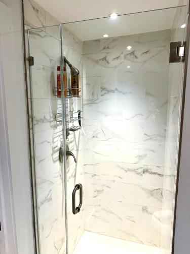 a bathroom with a shower with white marble walls at Studio Apartment with Garden Jersey City in Jersey City