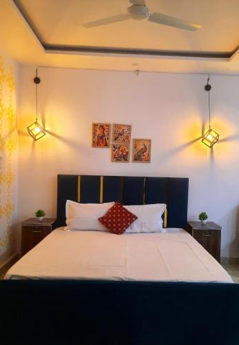 een slaapkamer met een groot bed met 2 lampen aan de muur bij The Moksha Residency By MOM'S in Prayagraj