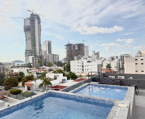 a swimming pool on the roof of a building with a city at Sundrift By GEstores in Mazatlán