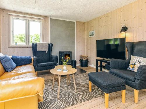 a living room with a couch and chairs and a television at 4 person holiday home in Hjørring-By Traum in Lønstrup