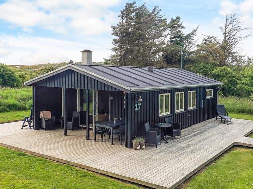 a black shed with a wooden deck in a yard at 4 person holiday home in Hjørring-By Traum in Lønstrup