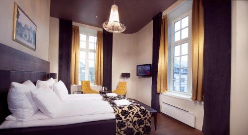 a bedroom with a large white bed and windows at Banken Hotel in Haugesund