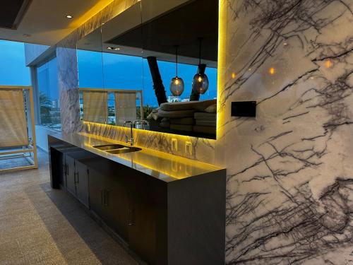Una cocina con encimera de mármol con fregadero. en Hermoso departamento 2 recámaras con alberca, en Nuevo Vallarta 