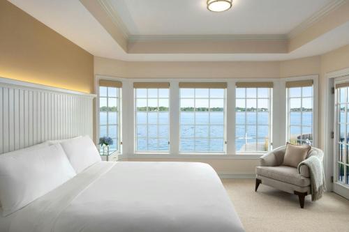 a bedroom with a bed and a chair and windows at St. Clair Inn in St. Clair