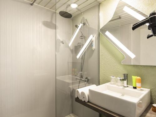 Un baño con lavabo, ducha y espejo. en ibis budget Saint-Ouen-l'Aumône, en Saint-Ouen-lʼAumône