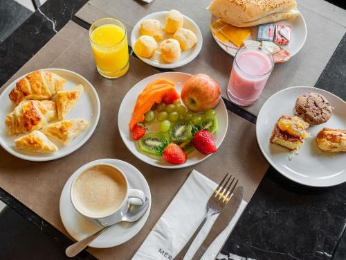 a table with plates of breakfast foods and a cup of coffee at Mercure Belem Boulevard in Belém