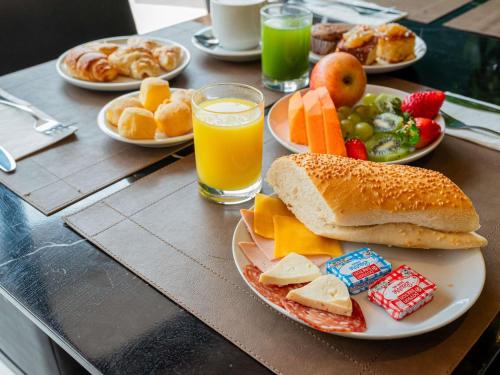 a table topped with plates of food and orange juice at Mercure Belem Boulevard in Belém
