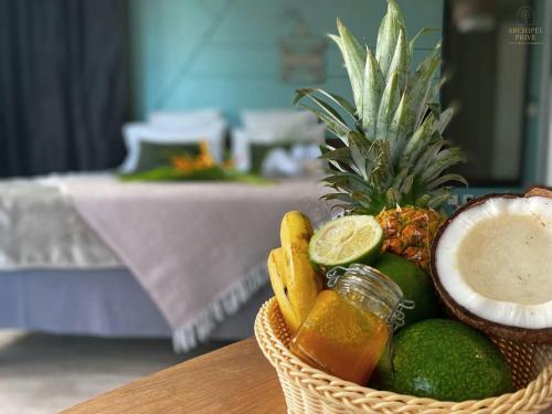 a basket filled with fruit and a pineapple and a pineapple at Archipel Guadeloupéen - Entre grand balcon, piscine & lagon - Élégant cocon d'architecte 2 étoiles in Saint-François
