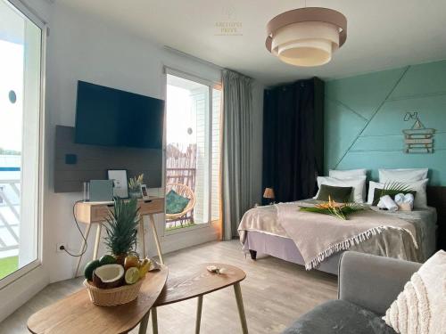 a bedroom with a bed and a table and a couch at Archipel Guadeloupéen - Entre grand balcon, piscine & lagon - Élégant cocon d'architecte 2 étoiles in Saint-François