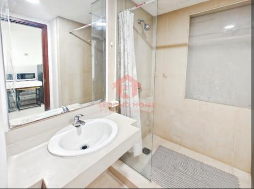 Un baño blanco con lavabo y ducha. en Newly Studio Nyaman U Residence 2, en Bojongrarang