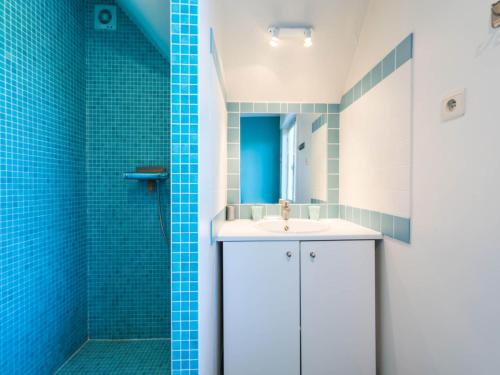 a bathroom with a white sink and blue tiles at LAuthentique in Sint-Idesbald