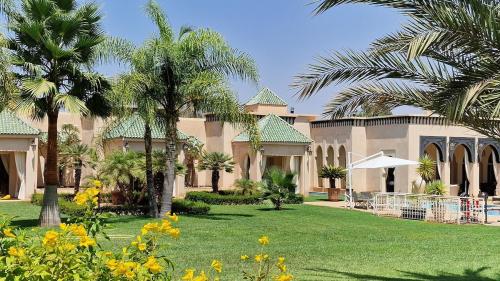 a large house with palm trees in a yard at Villa Alcázar Marrakech in Had Abdallah Rhiat