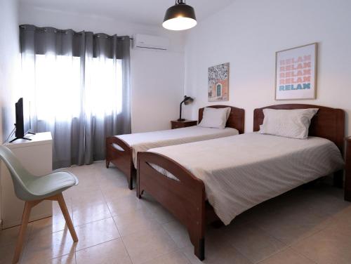 1 dormitorio con 2 camas, silla y TV en Hospedaria Portuguesa, en Alpiarça