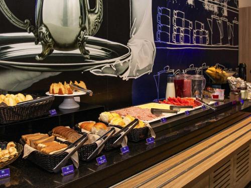 a buffet line with different types of bread and pastries at ibis budget Itaperuna in Itaperuna