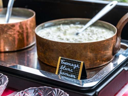 two large pots of food on a table with a sign at greet Hotel Beaune in Beaune