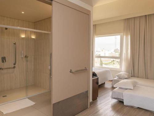 a bathroom with a shower and a glass door at ibis Styles Curitiba Aeroporto in São José dos Pinhais