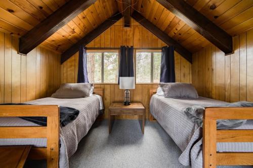 a bedroom with two beds in a wooden cabin at Hidden Pines Cabin - Nearby Snow & Play in Big Bear City Airport