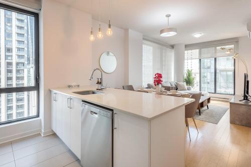 a white kitchen with a sink and a living room at Corner 2BR Old Port - Free Indoor Parking in Montreal