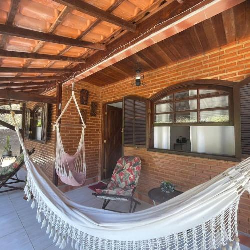 a porch with a hammock and a chair on a house at Casa no centro in Miguel Pereira