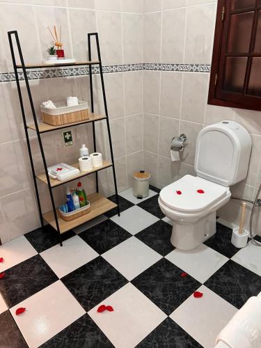 a bathroom with a toilet and a black and white checkered floor at Retiro encantador em Machico - 5 min Praia e Centro A in Machico