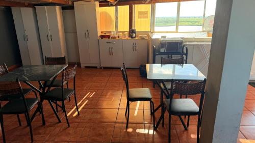 a dining room with tables and chairs and a kitchen at Pousada carioca in São João da Barra