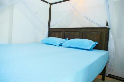 a bed in a tent with two blue pillows at Amible Guest Home in Mirissa
