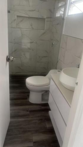 a white bathroom with a toilet and a sink at Full apartment near El Poblado in Medellín