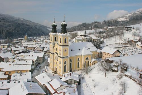 a church in a town with snow covered roofs at Appartements Altes Gericht in Hopfgarten im Brixental