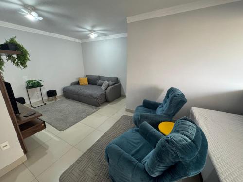 a living room with two blue chairs and a couch at Apartamento super central até 10 pessoas in Divinópolis