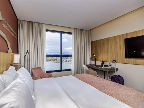 a hotel room with a large bed and a desk at Mercure Itajai Navegantes in Itajaí