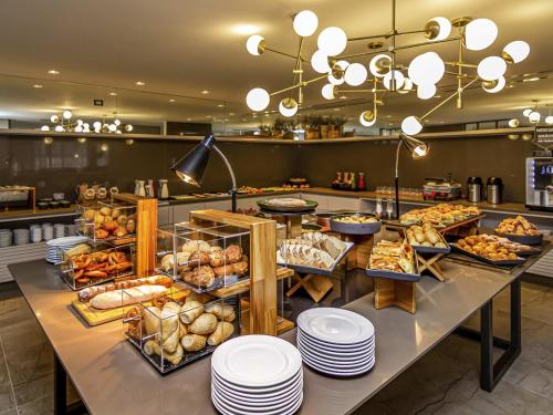 a buffet line with various types of bread and pastries at Mercure Itajai Navegantes in Itajaí