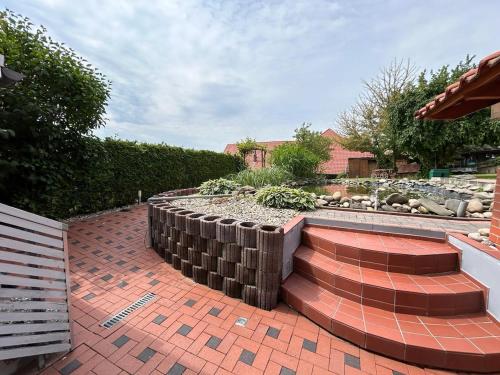a brick patio with a retaining wall and a garden at Ella-ruhiges 3-Zimmer-Ferienapartment im Grünen mit Netflix, Koiteich und Terrasse 