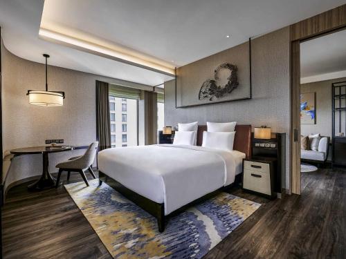 a hotel room with a large white bed and a desk at Pullman Bandung Grand Central in Bandung