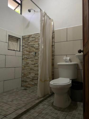 a bathroom with a toilet and a shower at Villa Granja Agua Azul-wi-fi-AC-6 Personas-parqueo in Agua Azul