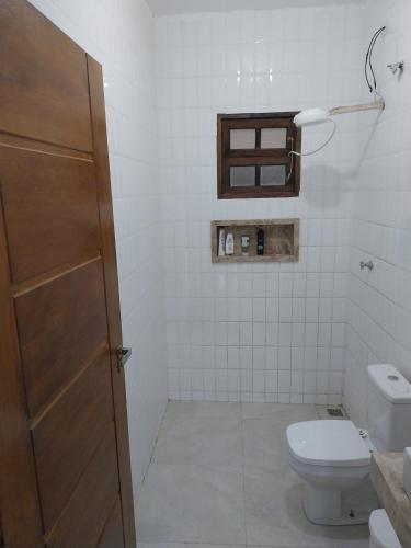 a white bathroom with a toilet and a sink at Casa da matta in Ubatuba