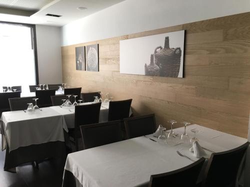 un comedor con mesas blancas y sillas negras en Hotel Calabria en La Garriga
