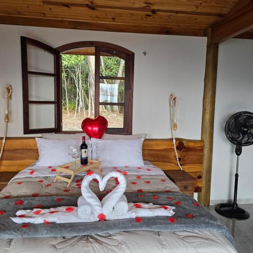 a bed with two towels in the shape of hearts at Chalé Pôr do Sol in Cunha
