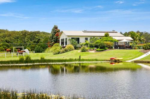a house with a pond in front of a house at The Sanctuary - Family Retreat - Noosa Hinterland in North Arm